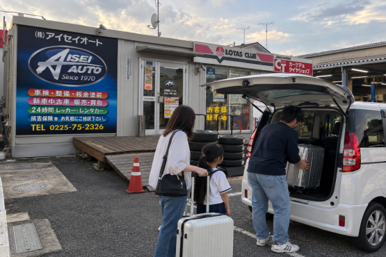 夕暮れの整備工場で旅支度する家族